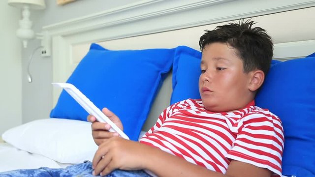 Child lying on a bed and watching television