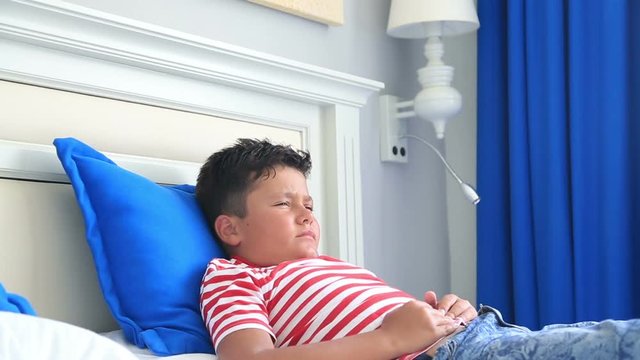 Child having a painful stomach ache andlying on a bed with hands on abdomen