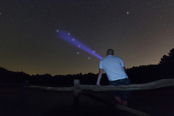 Man with a flashlight pointing to big dipper. Starry night Polaris star, Ursa Major, Big Dipper constellation. Beautiful night sky. Clear sky concept and background