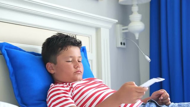 Child with remote controller lying on a bed and sleeping