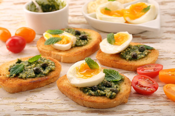 Fresh sandwich with pesto and egg on wooden background