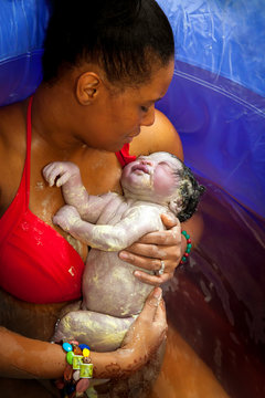 Mother Cradels Newborn In Birthing Tub