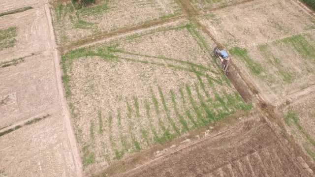 Aerial shot of tractor driving on countryside road with fields on both side in 4k video