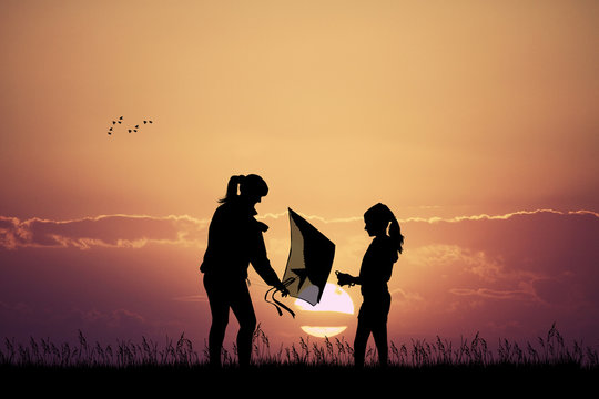 mom and girl with kite at sunset
