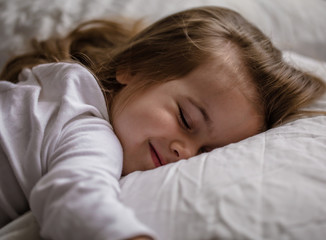 little girl falls asleep in bed on white pillow