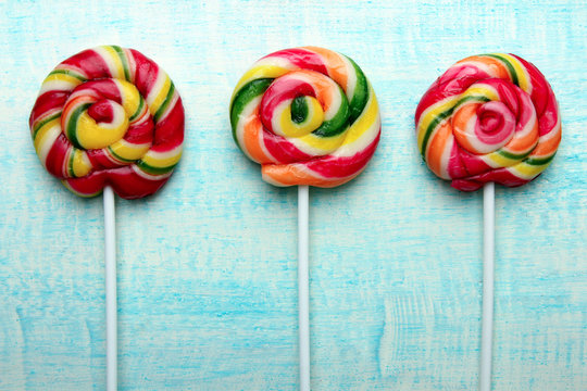 Swirling colorful lollipops on blue wooden background..