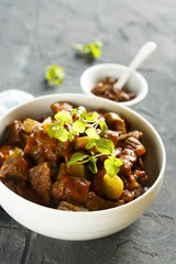 Goulash, served in white bowl with fresh herbs