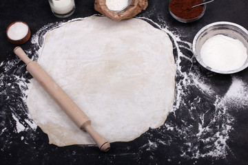 the rolled out dough with flour on black background