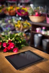 Naklejka na ściany i meble Bunch of red roses and digital tablet on the wooden table