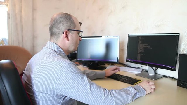 male programmer fixes the code sitting at the computer. side view