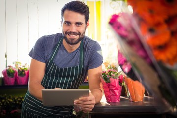 Male florist holding digital tablet at his flower shop