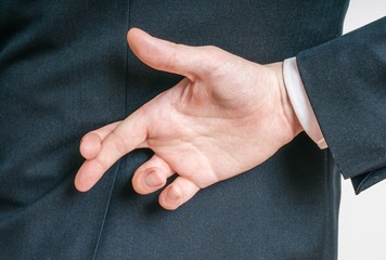 Businessman has crossed fingers behind his back. Good luck or dishonesty concept.