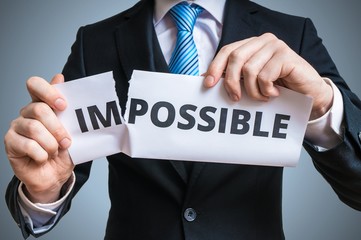 Obraz premium Possibility concept. Businessman is tearing paper with impossible word to make it possible.