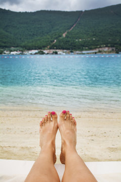 Relaxed female's feet against a beautiful blue sea
