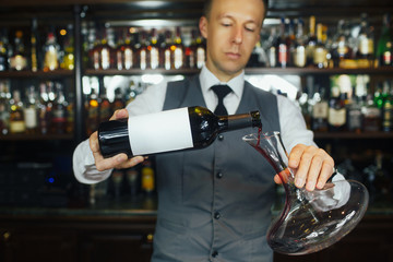 Sommelier pouring wine to the decanter in the wine cellar
