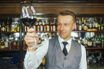 Quality examination. Selective focus on a shot of a professional smiling sommelier examining wine in a glass