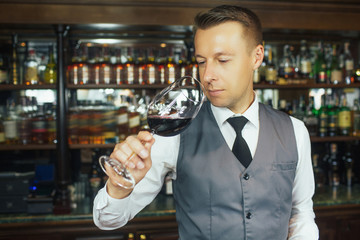 Quality examination. Selective focus on a shot of a professional smiling sommelier examining wine in a glass