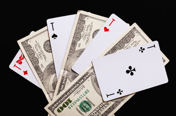 playing cards and hundred-dollar bills on a black background.