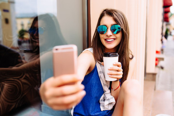 Attractive woman taking photo with take-out coffee on her phone