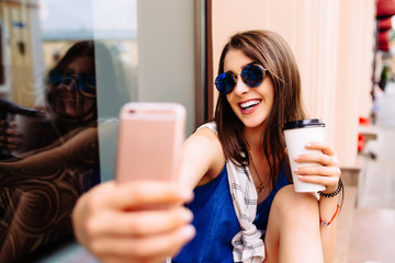 Attractive woman taking photo with take-out coffee on her phone