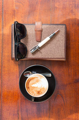 Notebook pen coffee and shades on wooden table