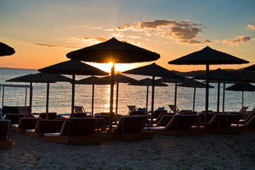 Straw parasols on a beach at sunset in Sithonia, Greece