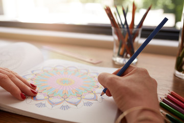 Human hands drawing in adult coloring book © Jacob Lund