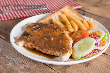 Juicy grilled pork with garlic sauce and salad, french fries.