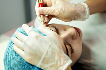 Cosmetician making permanent eyebrow make up