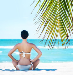 Back of a young woman relaxing on a tropical beach