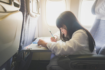 Asian girl painting with color pencil on airplane
