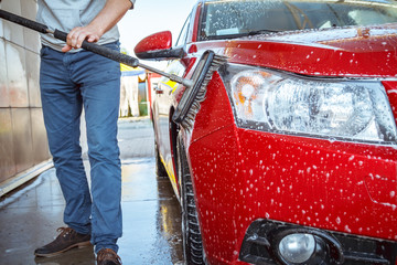 Contactless car wash self-service. Young man washing his car