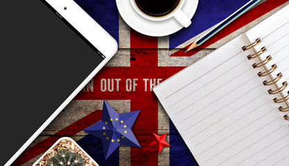 get britain out of europe concept, tablet computer,  coffee cup and notebook with united kingdom flag painted on old wood plank background, high contrast and over light