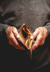 Empty wallet in the hands of an elderly man. Poverty in retirement concept - obrazy, fototapety, plakaty