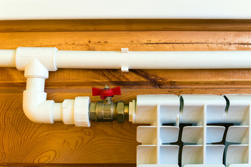  Heating radiator and polypropylene pipes in a wooden house 