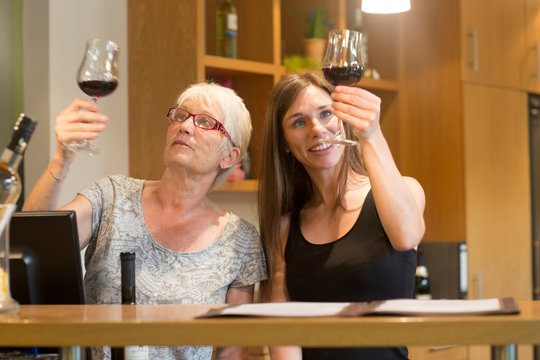 Women at counter in wine bar checking clarity of wine