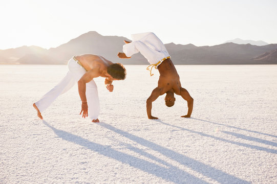 Two men on Bonneville Salt Flats performing capoeira, Utah, USA
