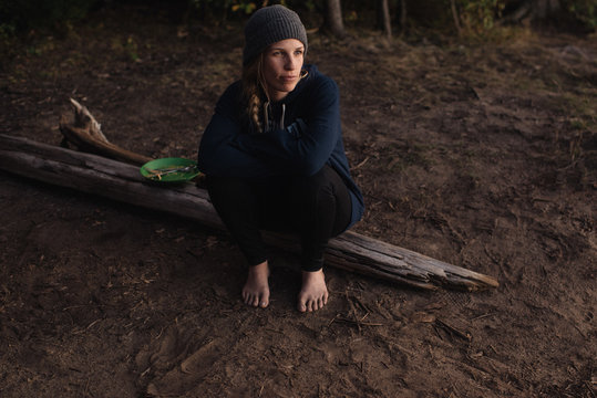 Mid adult woman sitting on wood in forest, looking away