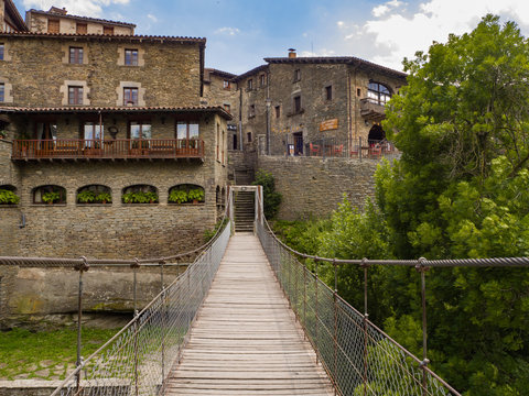 Puente colgante de madera con vistas a las fachadas de las casas de piedra del pueblo medieval de Rupit en Osona Barcelona verano de 2016.