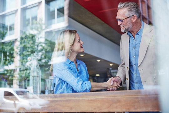 Mature Man And Woman Meeting In Cafe, Shaking Hands