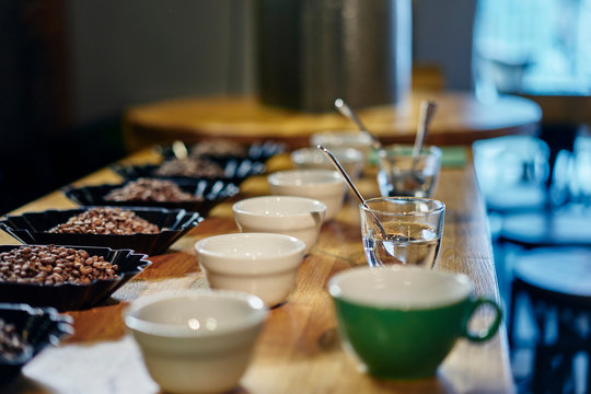 Rows of coffee beans and bowls for tasting on coffee shop counter