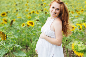 Fototapeta na wymiar Pregnant girl in the field with sunflowers