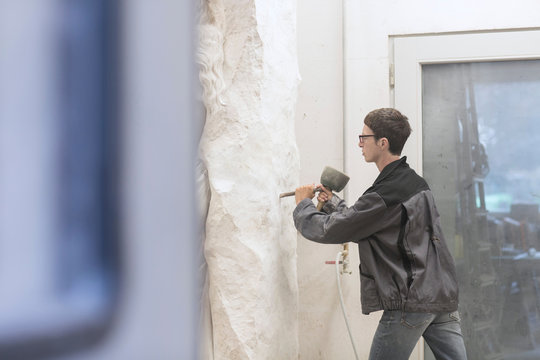 Stonemason using chisel and mallet to create sculpture