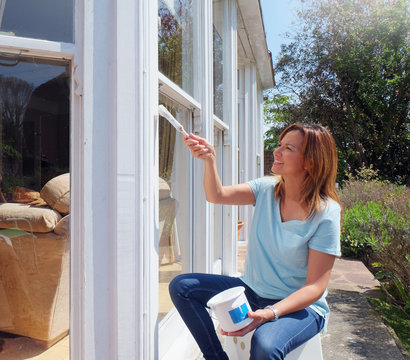 Woman painting window frame