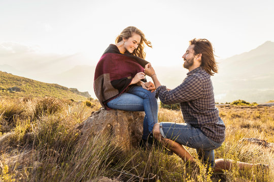 Man proposing to woman in meadow