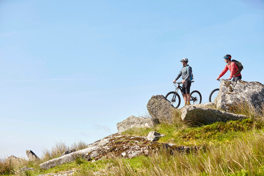 Cyclists on bicycles on rocky outcrop looking away
