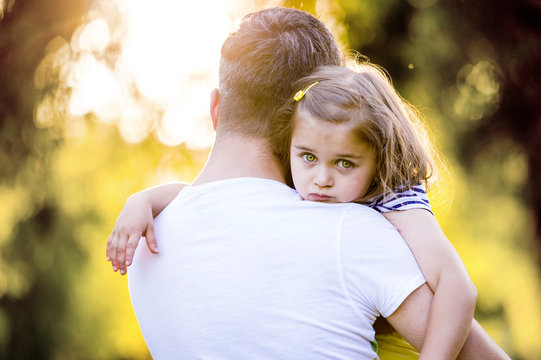 Portrait of sad little girl on father's arms