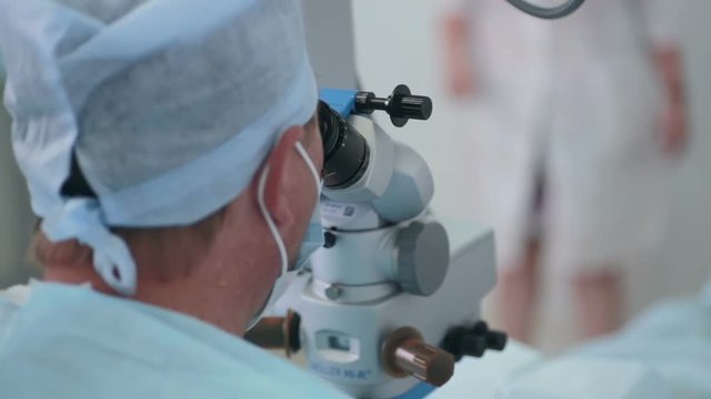 Unrecognizable Doctor looking in microscope during operation. 1080p.