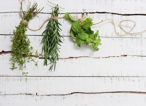 Thyme, rosemary and mint hanging on twine over white wood