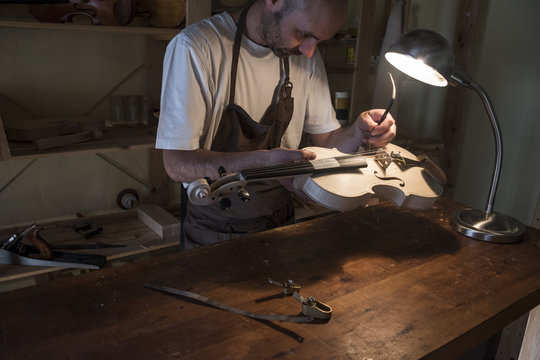 Luthier adjusting the sound post of a violin in his workshop